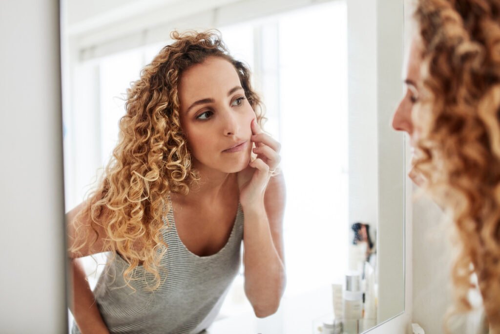 Woman Looks at Skin in Mirror with Concern Following FDA Warning about REnuvion Skin Tightening