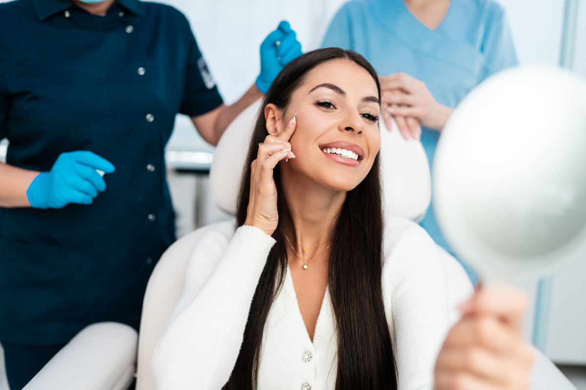 Woman looks at skin in mirror during a Boston Vivace RF microneedling consultation