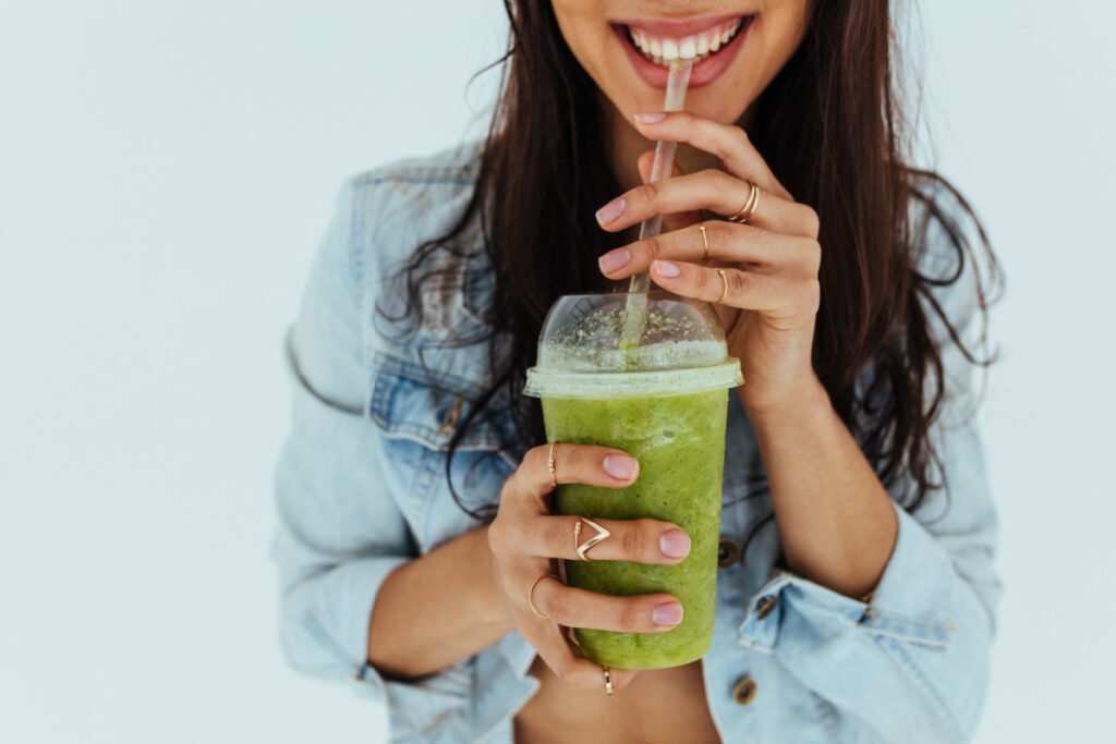 Woman smiling and drinking healthy green juice from local Boston wellness business