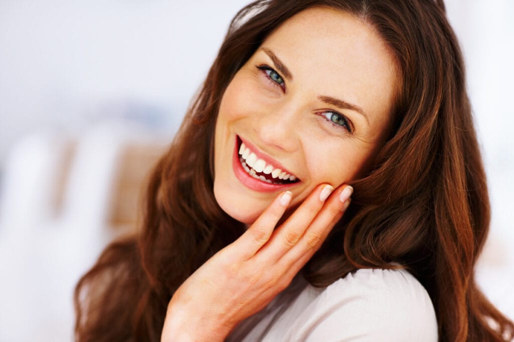 Brunette woman touching face and smiling